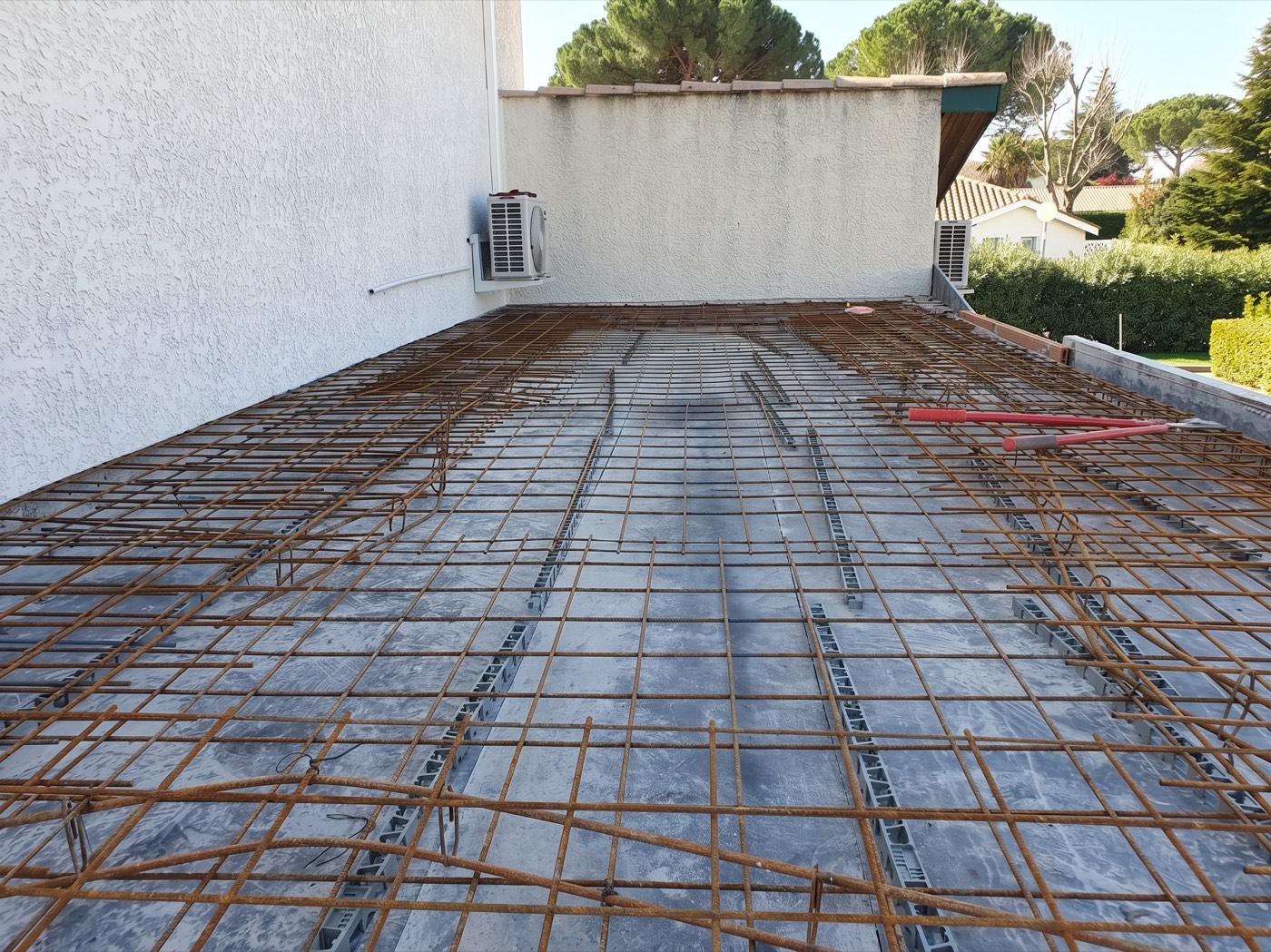 Ferraillage d’une dalle pleine posé sur coffrage, avant coulage du béton, le long d’une maison